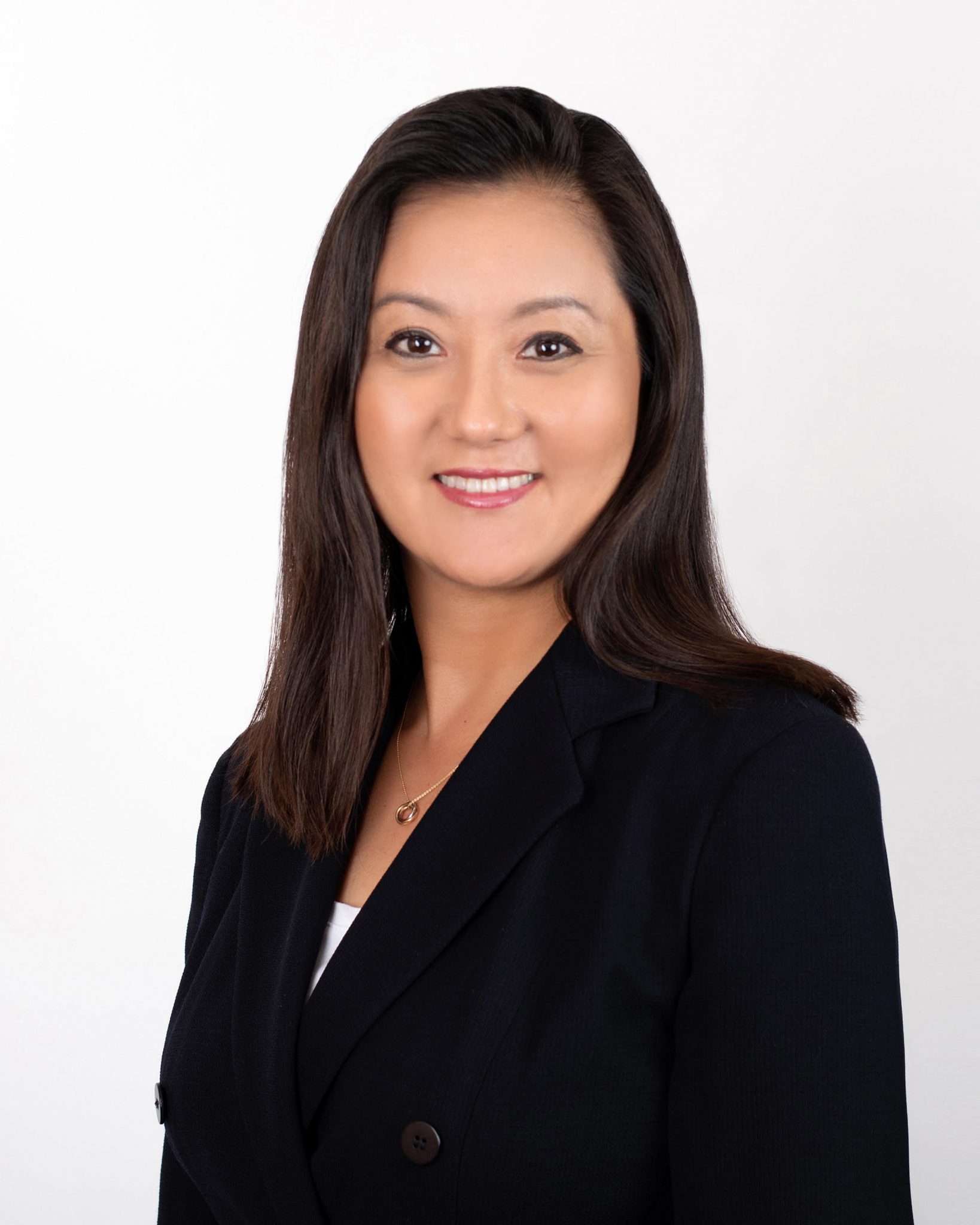 Professional woman with long dark hair wearing a black blazer, smiling confidently.